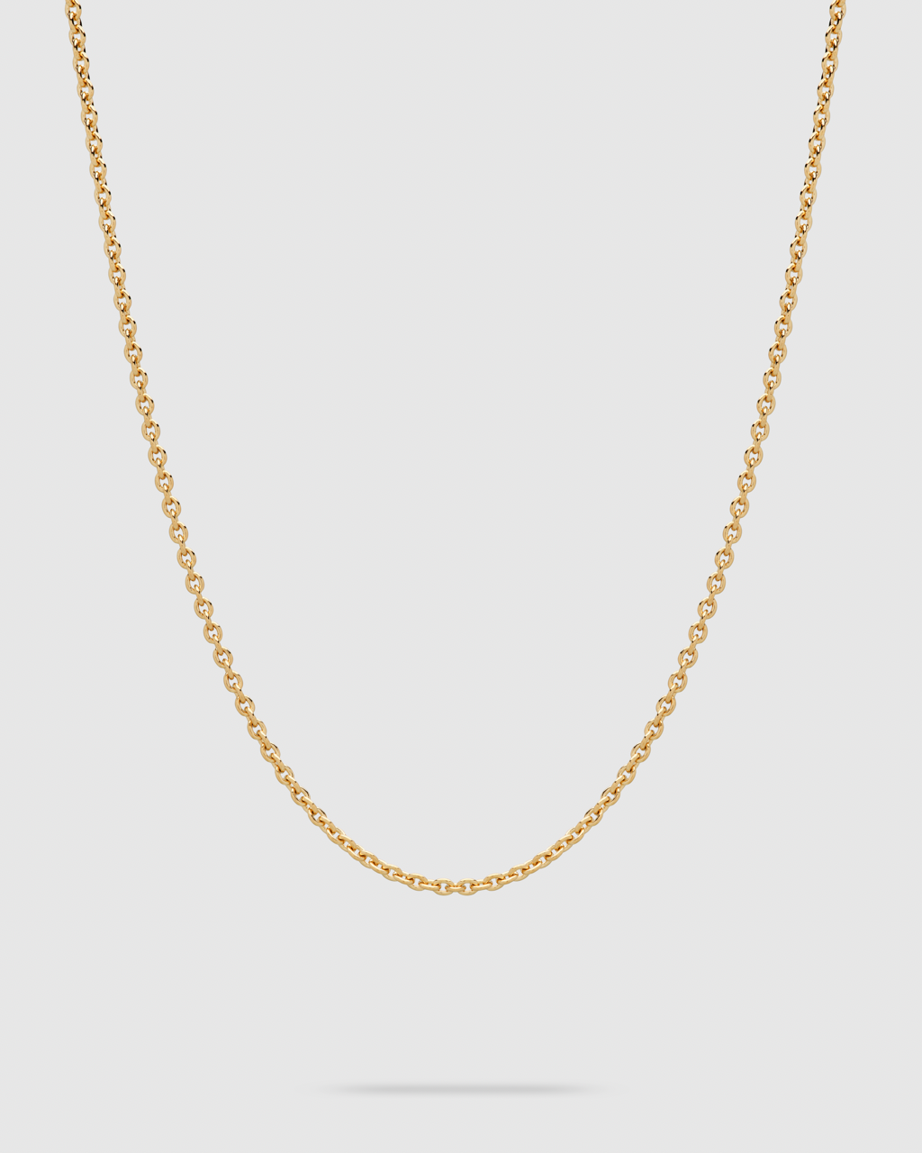 A delicate gold chain necklace with small, uniform links, displayed in a U-shape against a solid light gray background.