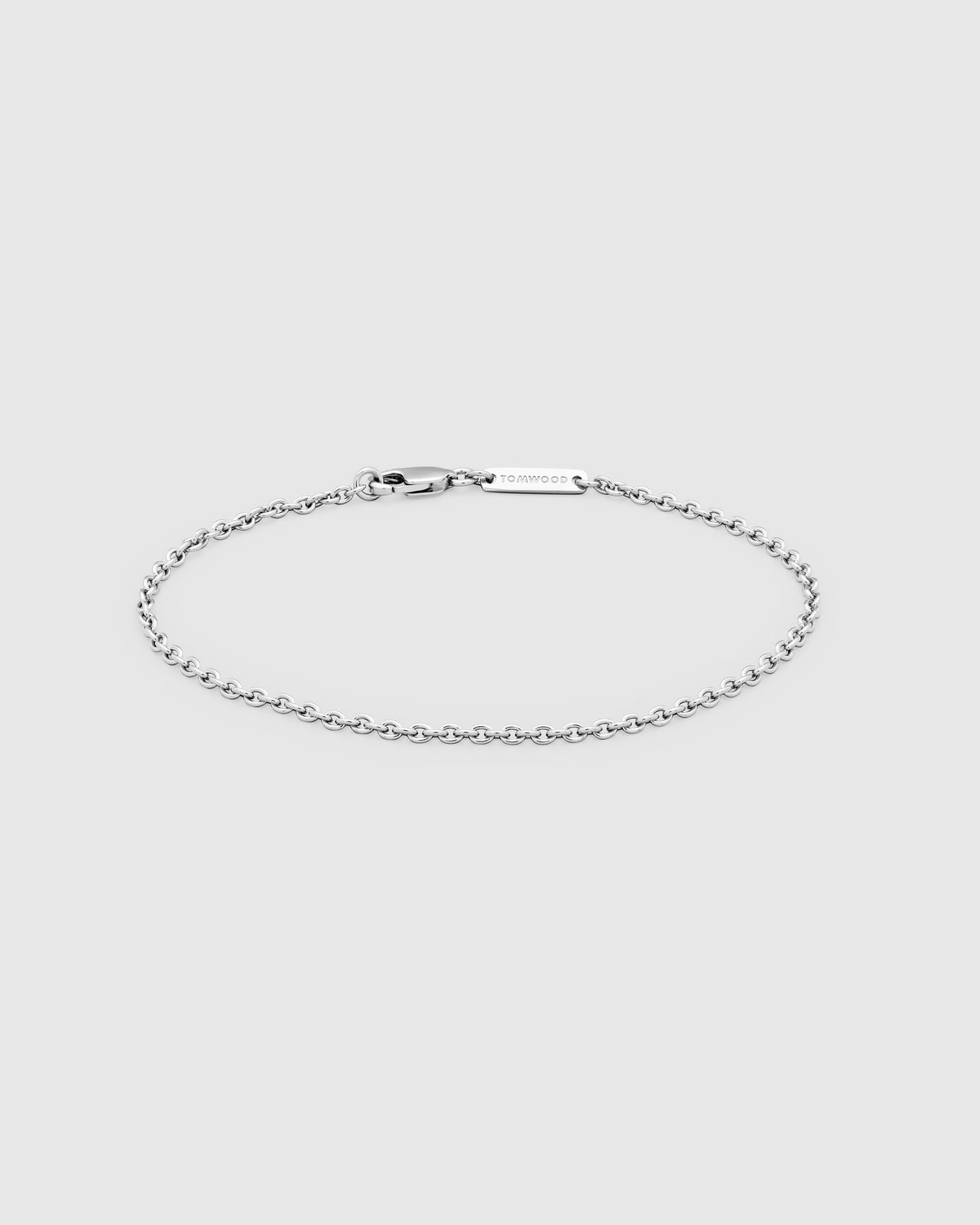 A delicate silver chain bracelet with a lobster clasp and a small rectangular engraved tag, displayed on a light gray background.