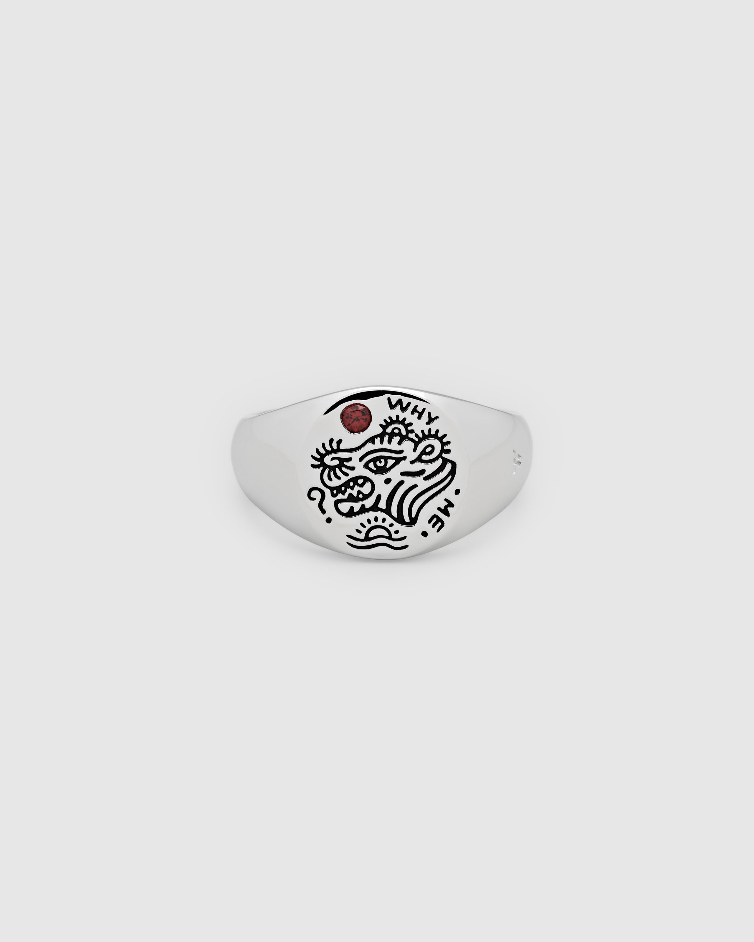 A small, round signet 925 sterling silver ring for men and women, featuring an engraved custom motif by Guy Le Tatooer and a hand-set, deep red garnet stone on the surface.