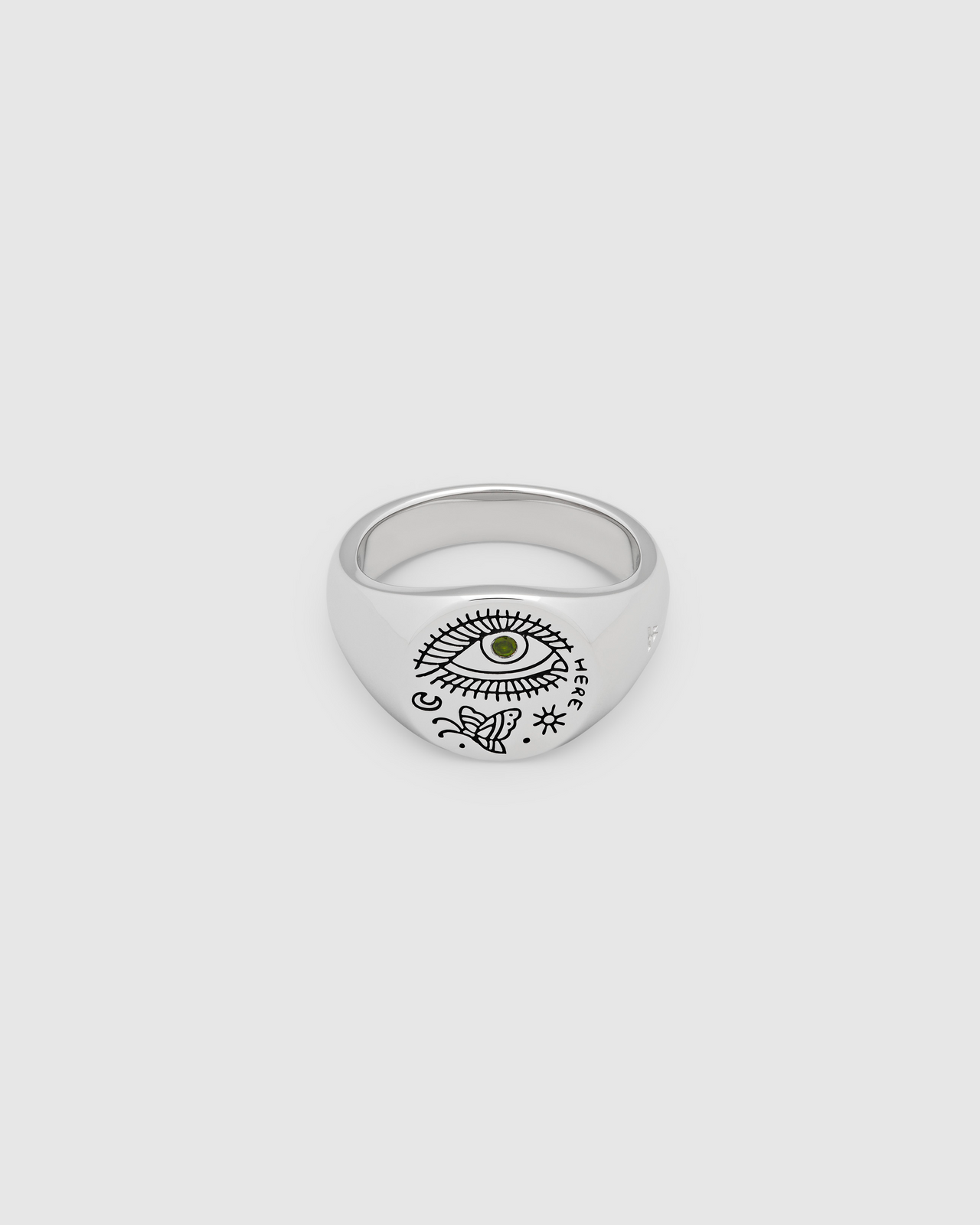 A small, round signet 925 sterling silver ring for men and women, featuring an engraved custom motif by Guy Le Tatooer and a hand-set, deep green tourmaline stone on the surface.