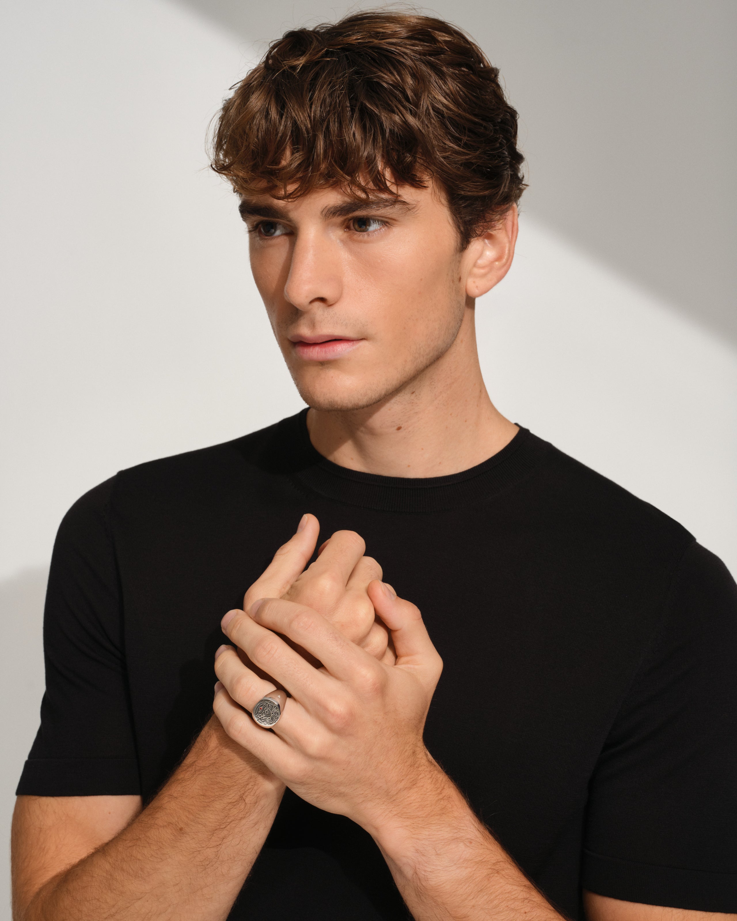 Man wearing a 925 sterling silver signet ring with engraved symbols in black antiquing and drawings from Guy Le Tatooer on a white background