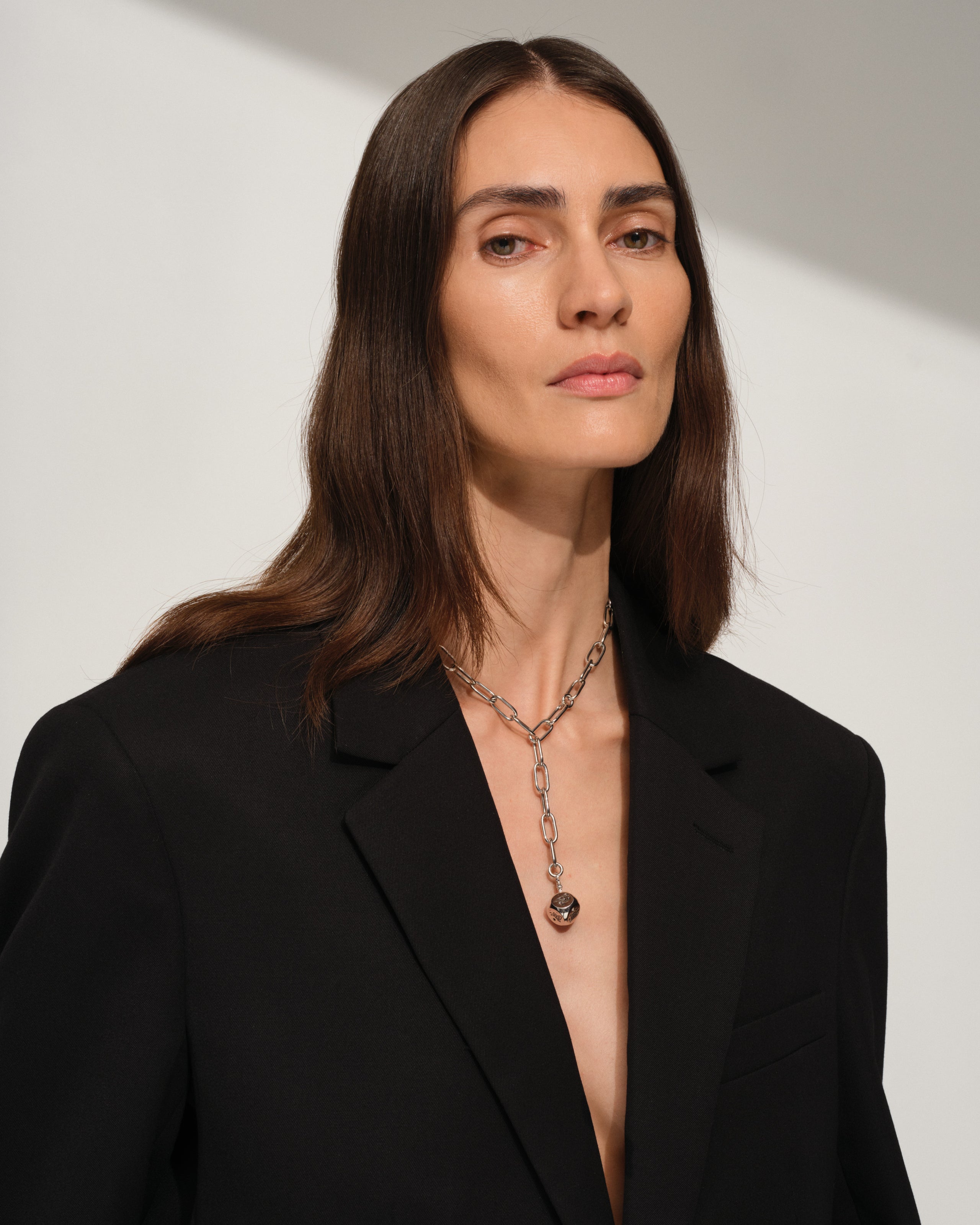 Woman wearing a black blazer with a sterling silver necklace with silver dice charm