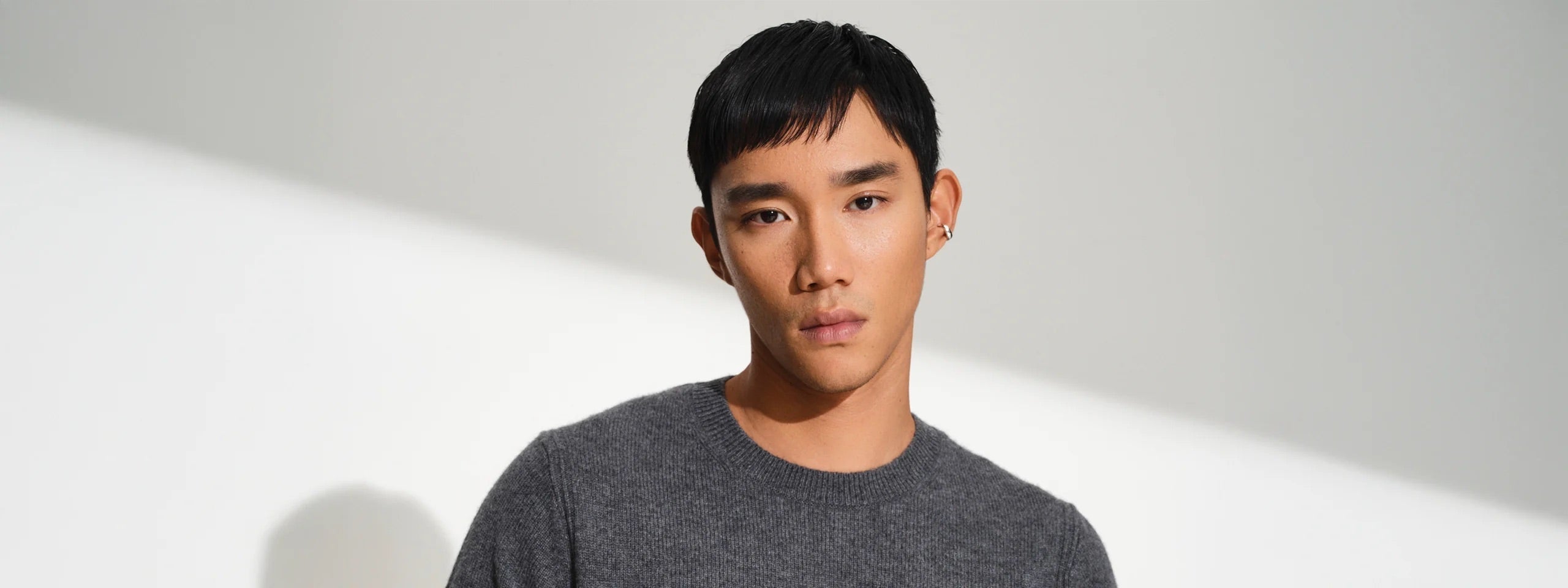 Man wearing a dark grey shirt and a subtle silver ear cuff.