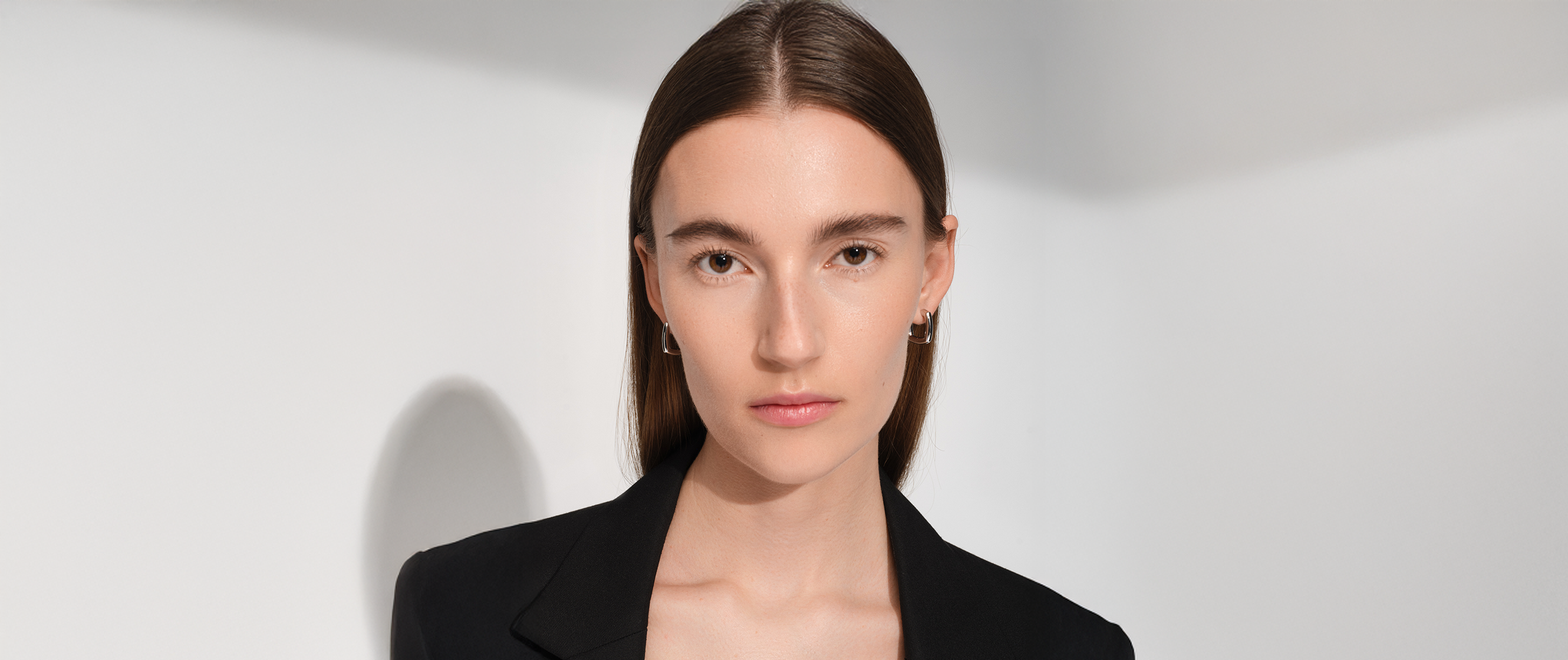 Woman in a black blazer wearing a sleek silver ear cuff.