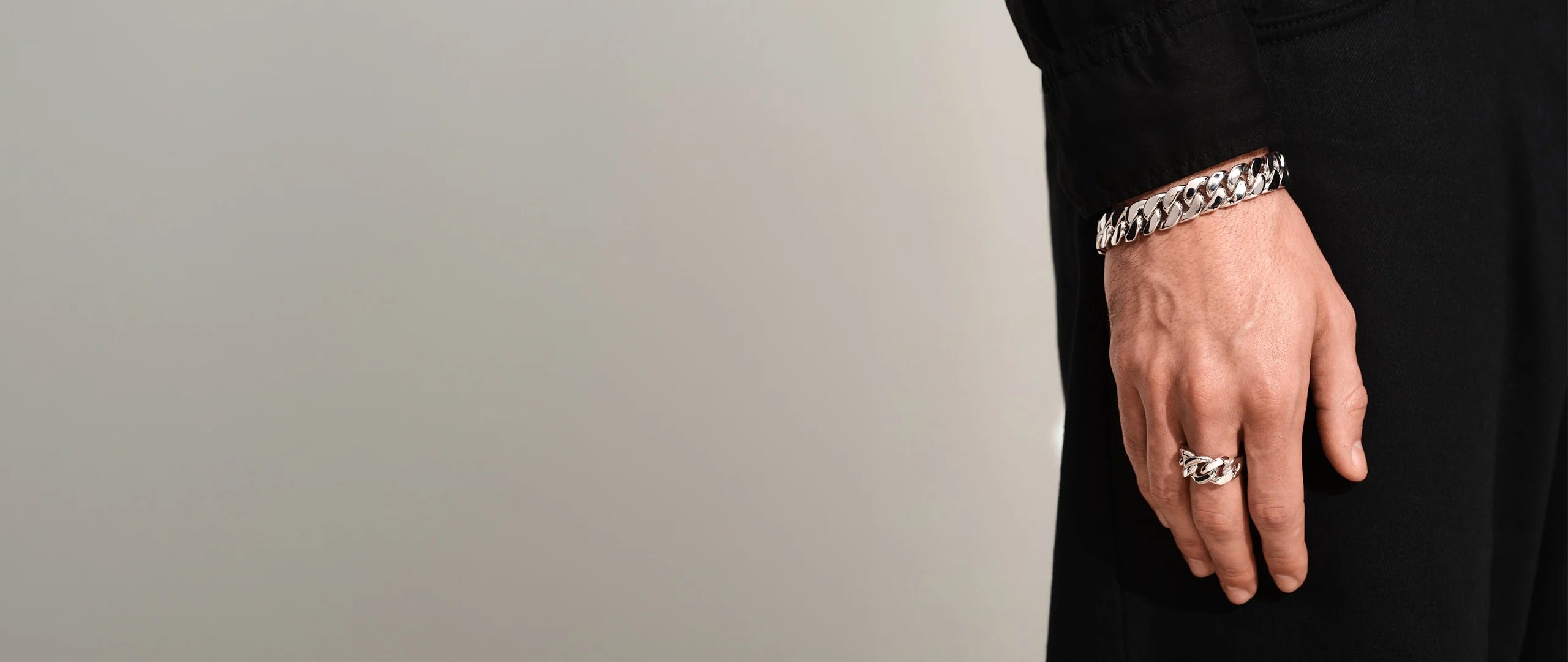 Model wearing a Tom Wood silver signet ring and chain bracelet in recycled sterling silver.