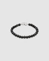 A beaded bracelet made of matte black round beads with a polished silver-toned lobster clasp, displayed on a light gray background.