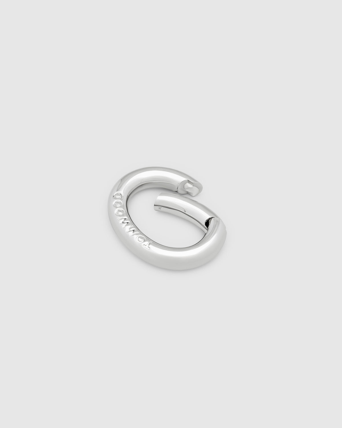A silver metal key clasp with a flat, circular design and the brand name 'TOMWOOD' engraved on the top, set against a solid light gray background.