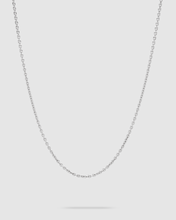 A delicate silver chain necklace with a small-scale link pattern, displayed against a solid light gray background.