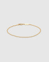 A delicate gold chain bracelet with a lobster clasp and a small rectangular engraved logo tag, displayed on a light gray background.