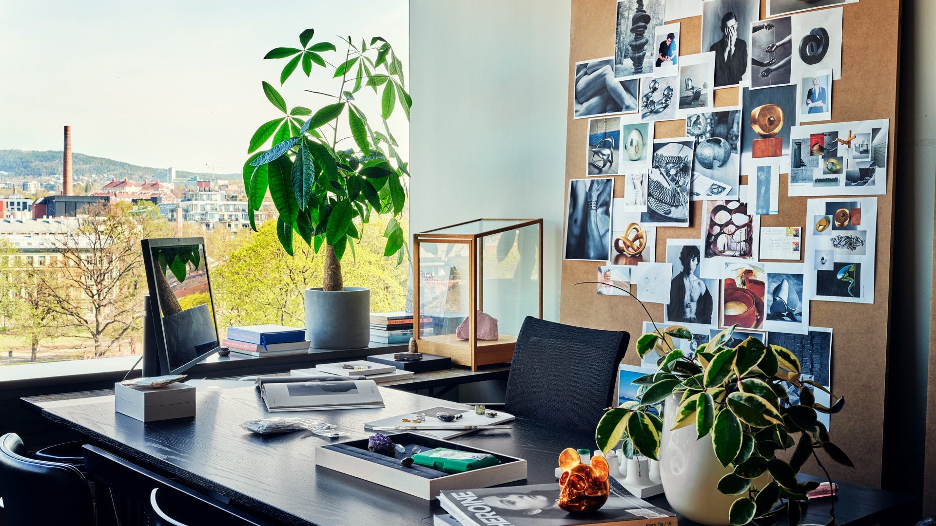 Modern office desk with plants, books, and a computer setup.