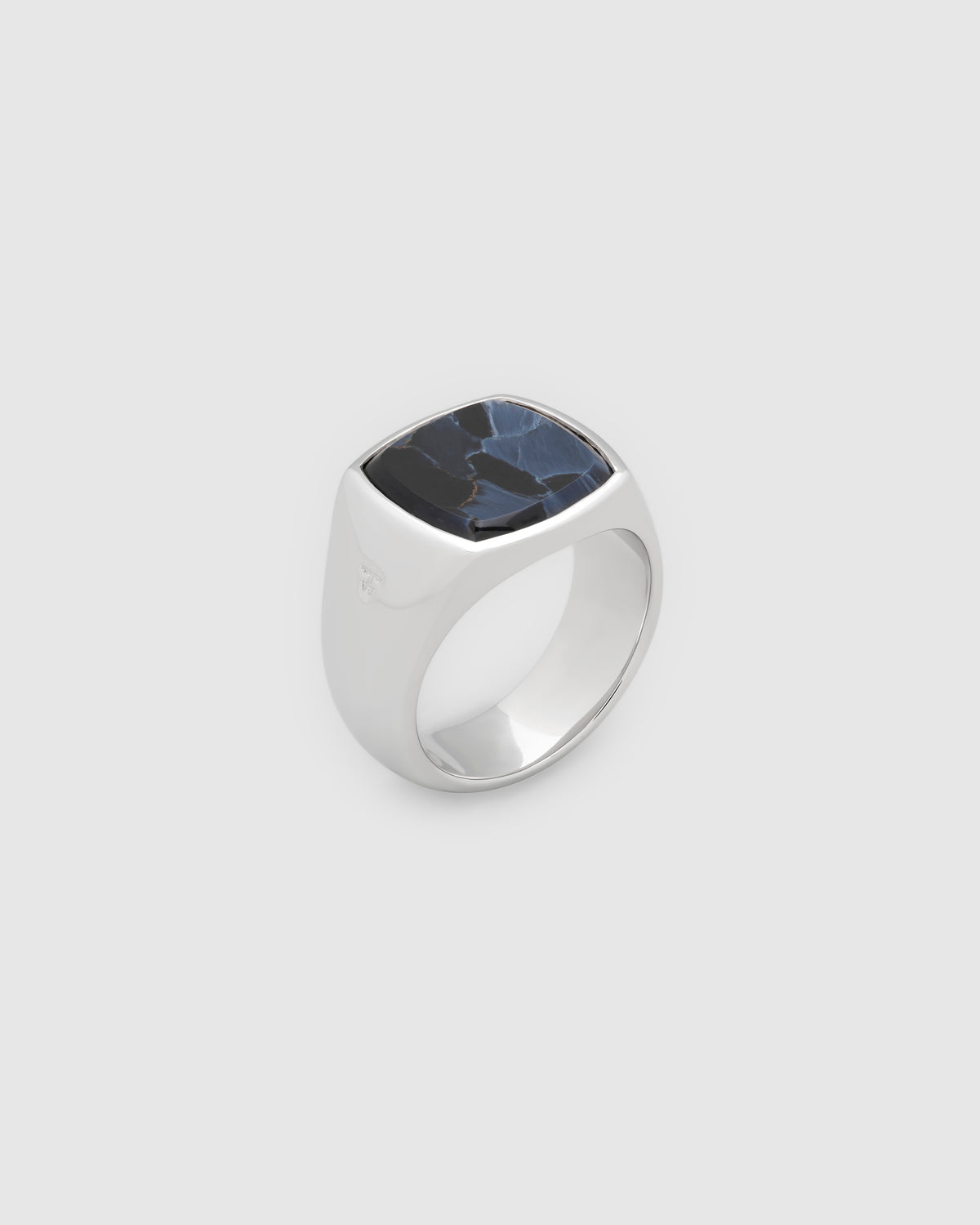 A silver signet-style ring with a square, cushion-cut dark blue pietersite stone featuring natural marbling, shown on a light gray background.
