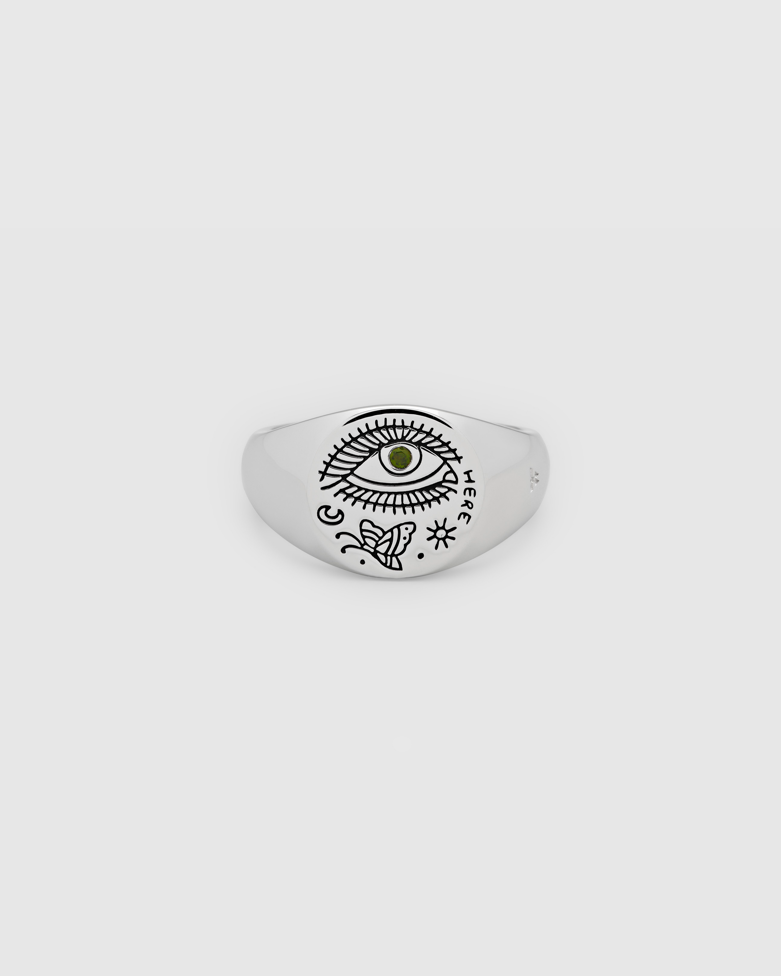 A small, round signet 925 sterling silver ring for men and women, featuring an engraved custom motif by Guy Le Tatooer and a hand-set, deep green tourmaline stone on the surface.