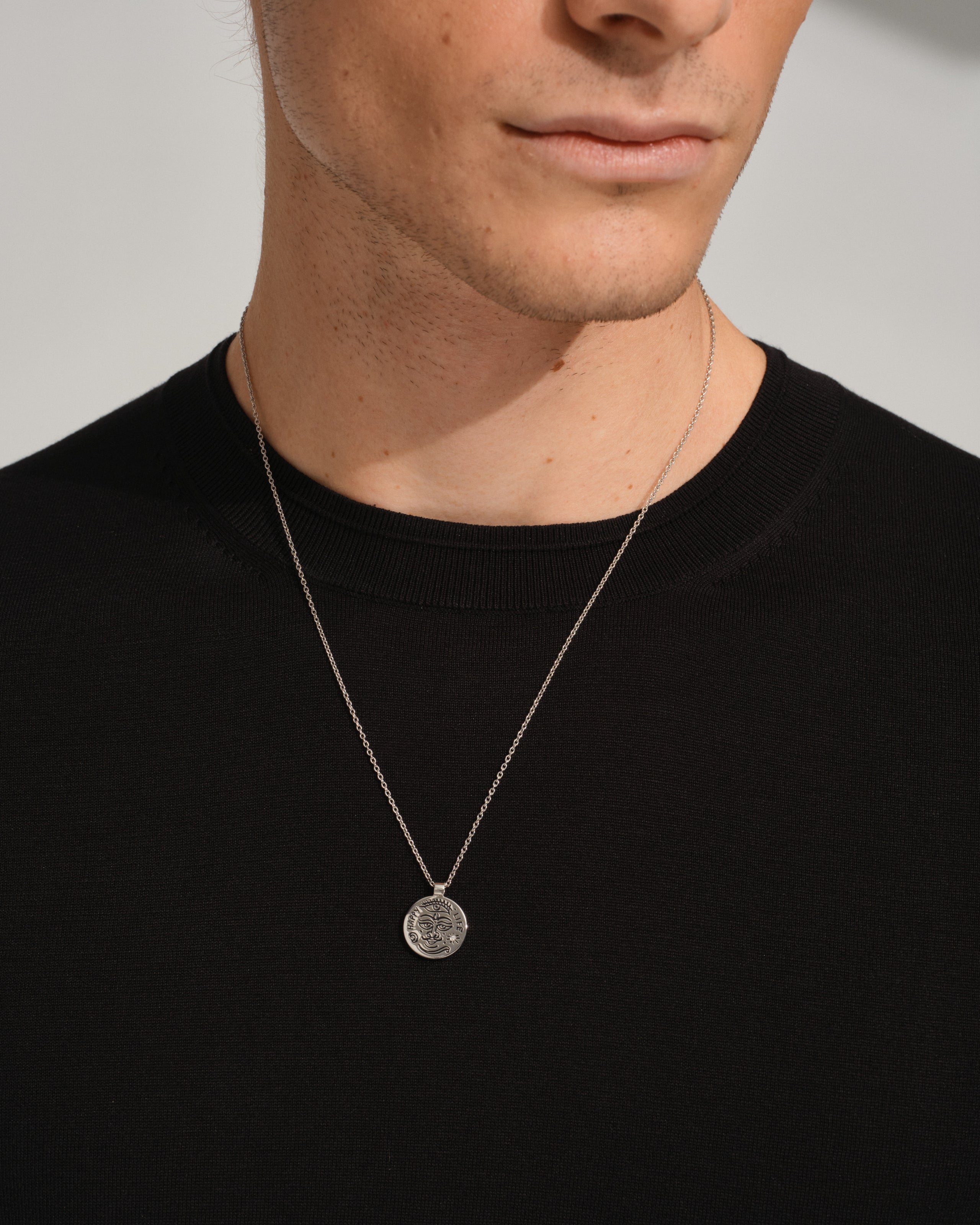 Man wearing a black shirt with a 925 sterling silver necklace with a featuring a round silver pendant with black antiquing.