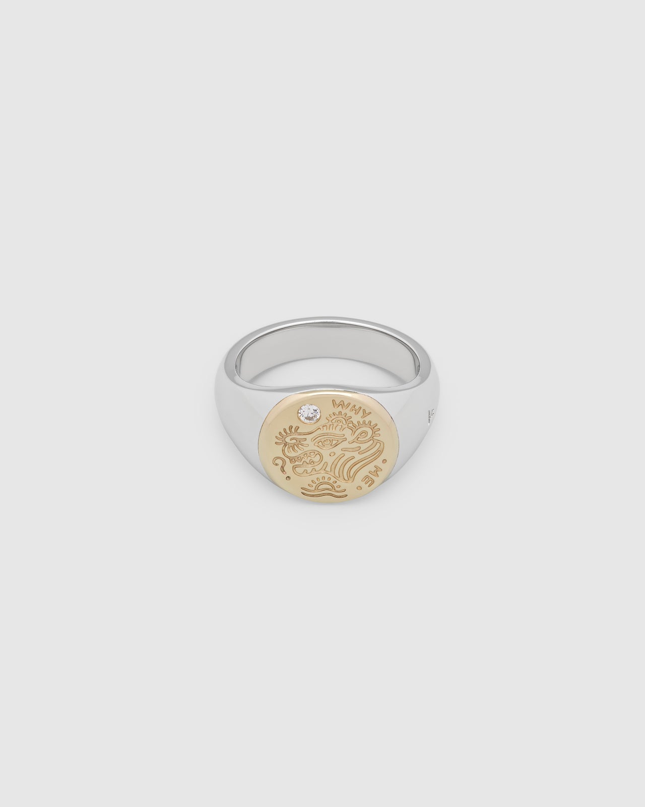 A small, round gold and 925 sterling silver signet ring for men and women, featuring an engraved custom motif from Gey Le Tatooer and a hand-set, lab-grown diamond on the surface.